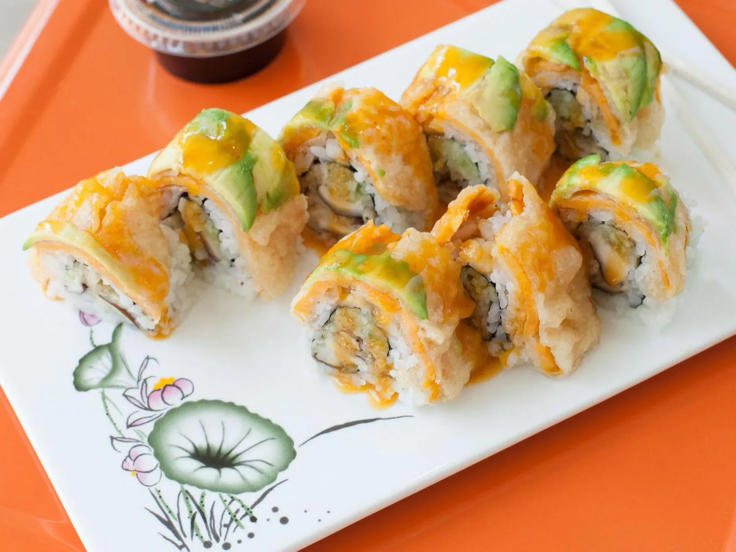Crispy sushi roll with avocado and orange sauce on white plate at Sushi Yoshi，a Japanese Restaurant in Brooklyn
