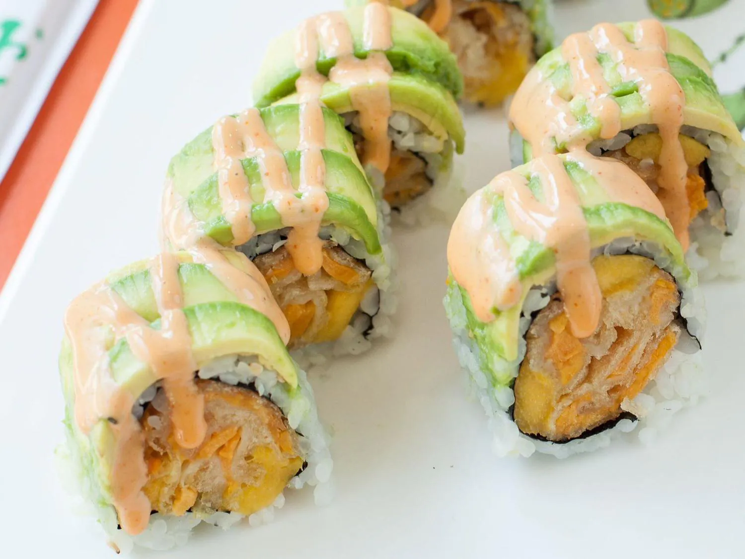 Avocado sushi roll with spicy pink sauce on white plate at Sushi Yoshi，a Japanese Restaurant in Brooklyn