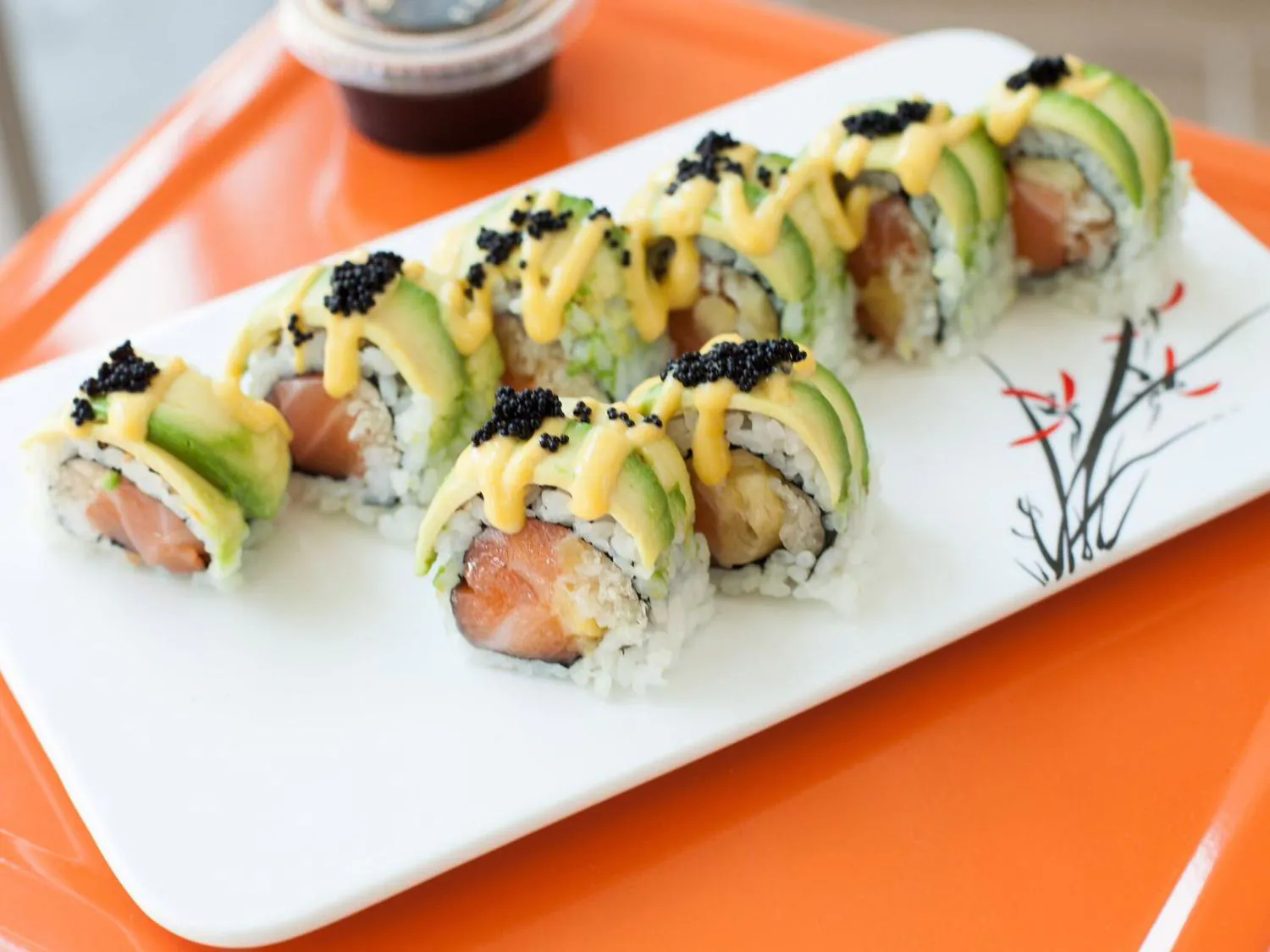 Avocado salmon sushi roll with black caviar and yellow sauce on white plate at Sushi Yoshi，a Japanese Restaurant in Brooklyn